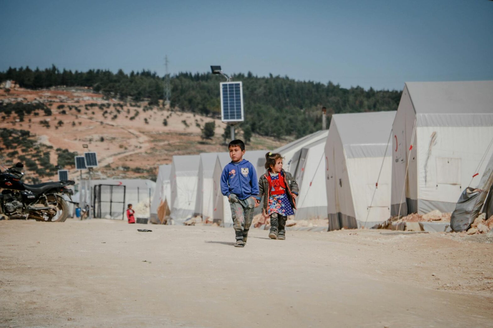 ethnic kids walking on road in refugee camp